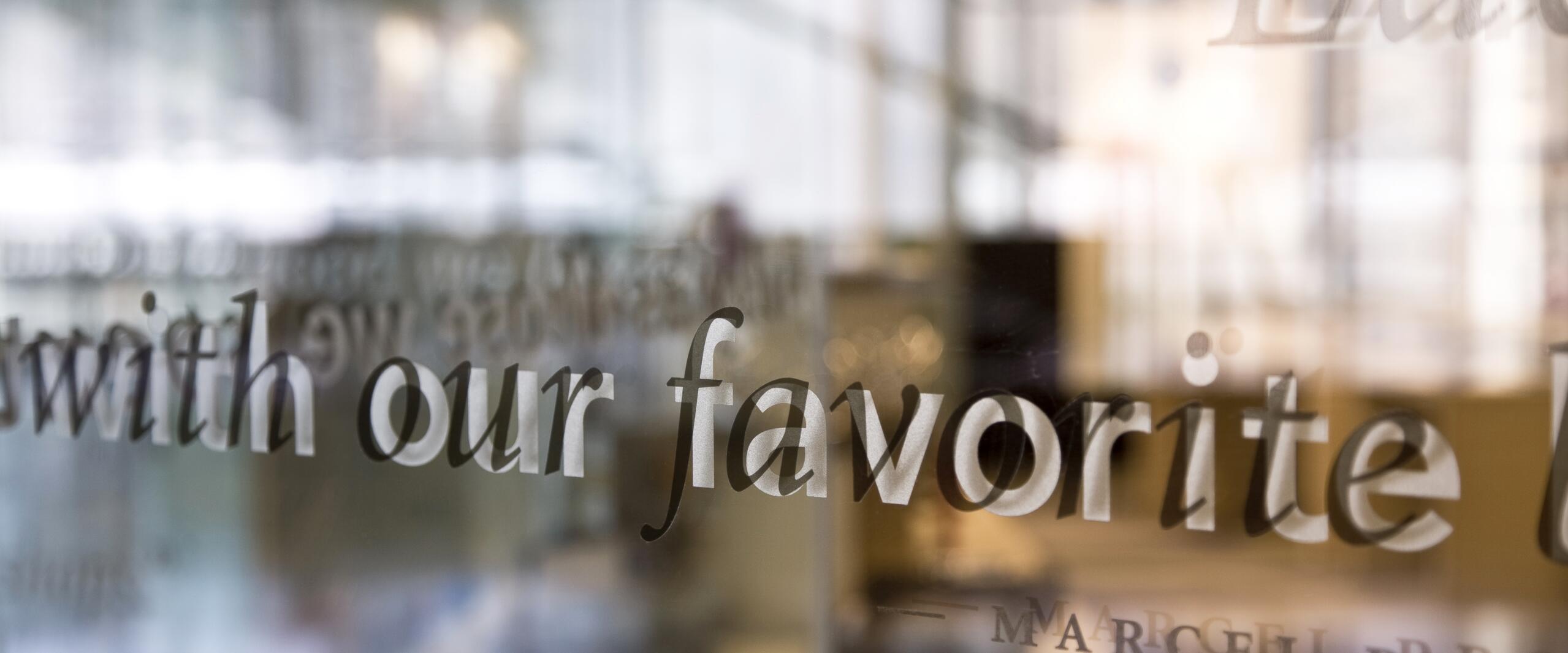 Text on glass reflecting a blurred office environment, with a phrase partially visible: "with our favorite."