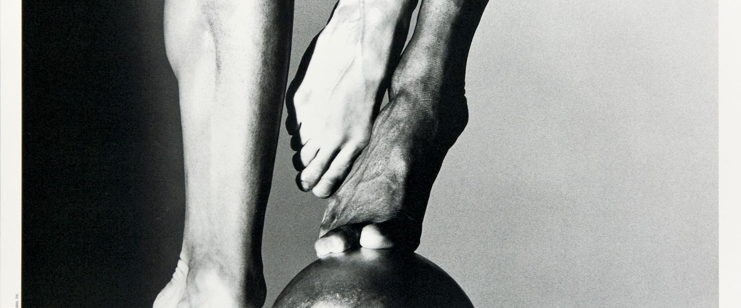Two dancers' legs and feet in black and white performing a pose on a large sphere, showcasing strength and balance. Text at the bottom reads, "Hubbard Street Dance Chicago."