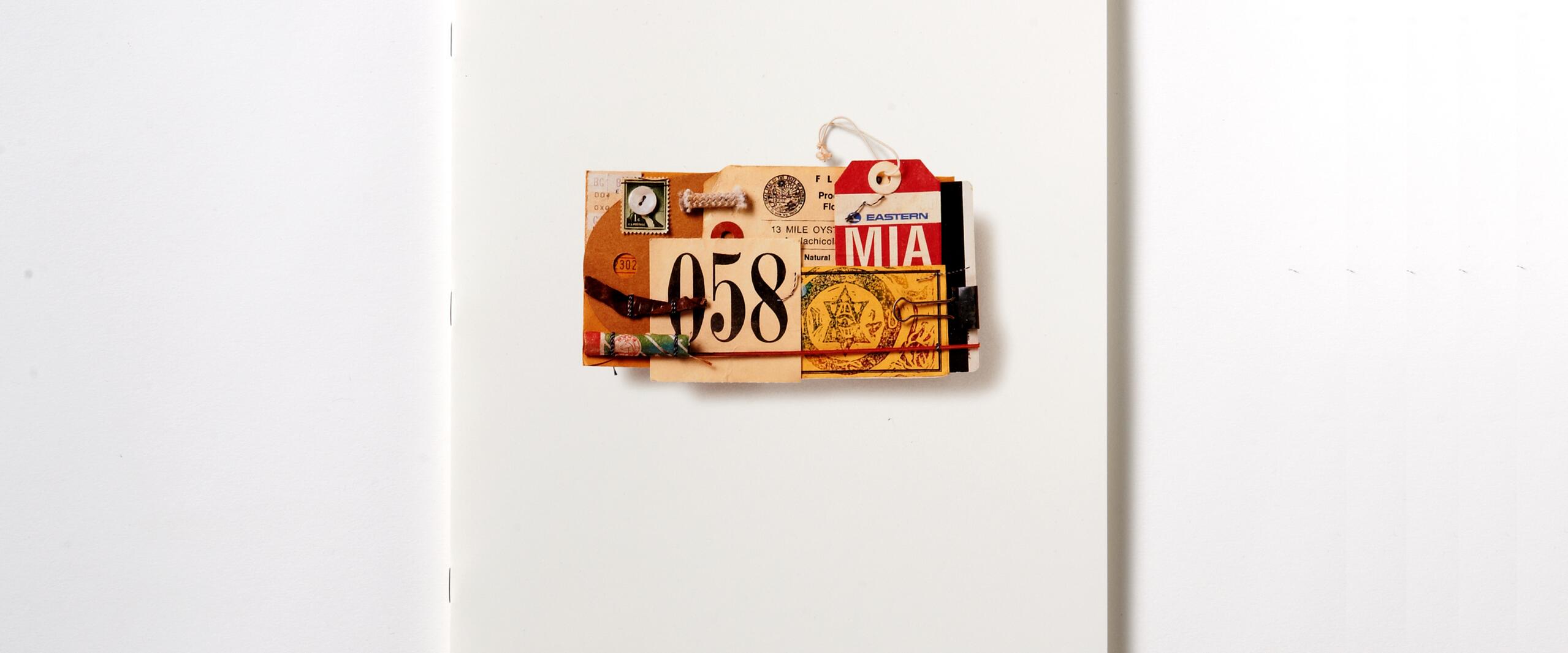 A collage with vintage travel tags and tickets is attached to a white booklet with faint text.