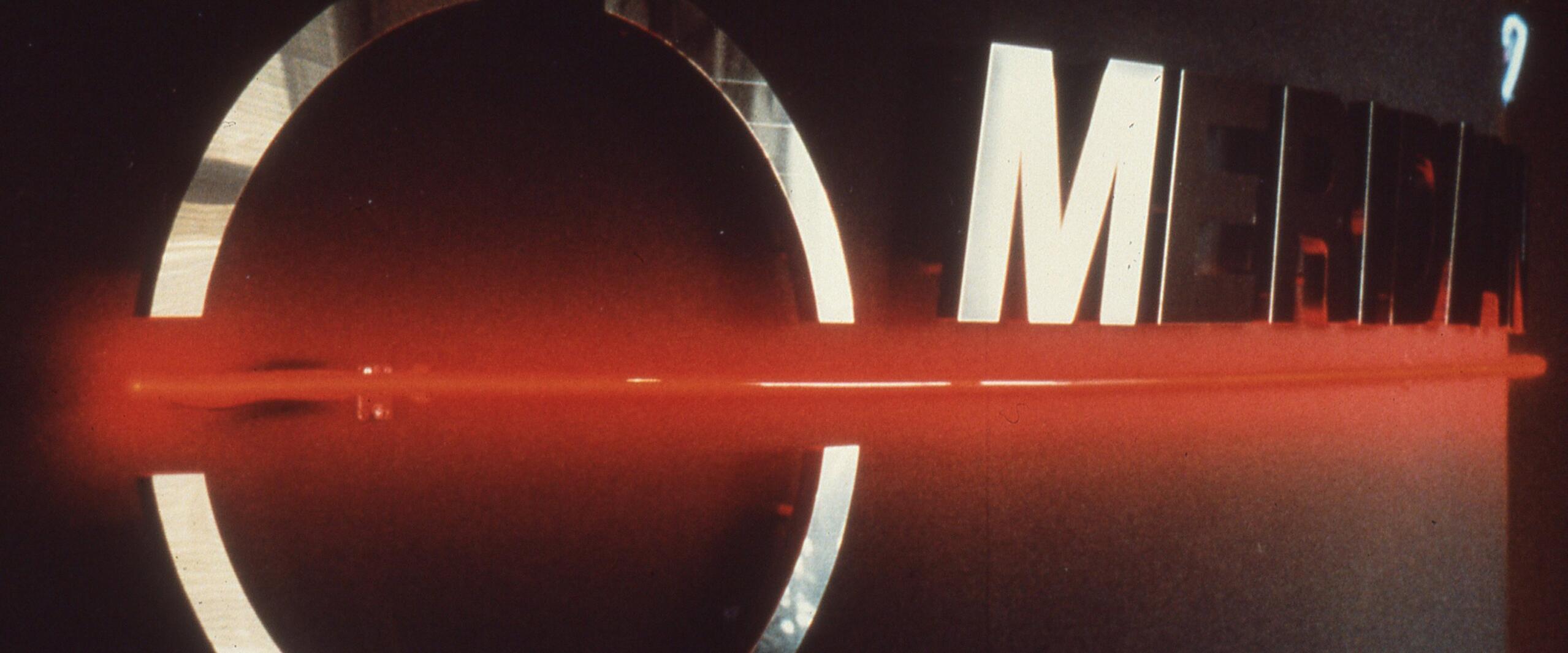 Red neon lighting emphasizes chrome letters spelling "MERIDIAN" on a dark background.