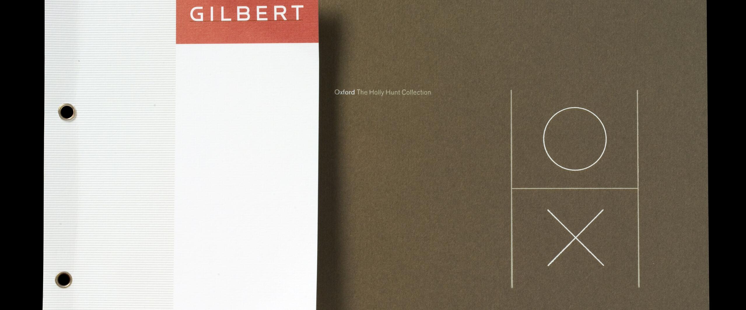 Two binder covers, one white with a red header labeled "GILBERT," and another brown featuring minimalist tic-tac-toe graphics with a circle and an "X."