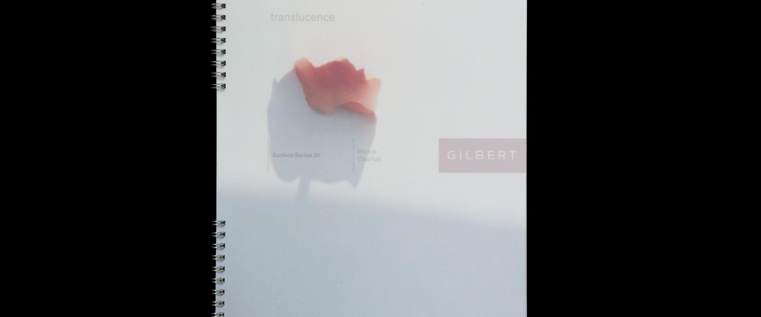 Spiral-bound notebook with a soft-focus image of a red flower on a white background, featuring the word "GILBERT" in a pink box.