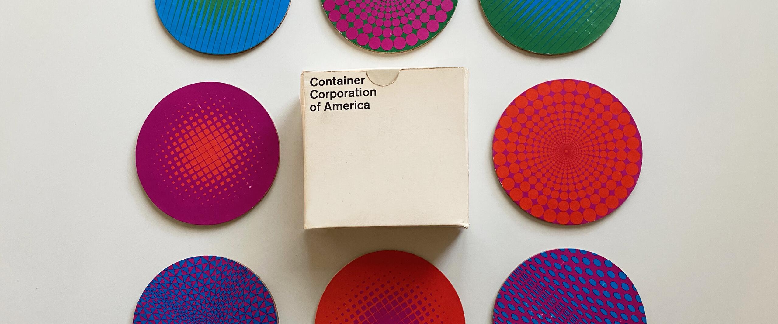 Colorful coasters with geometric patterns arranged around a small box labeled "Container Corporation of America" on a white surface.