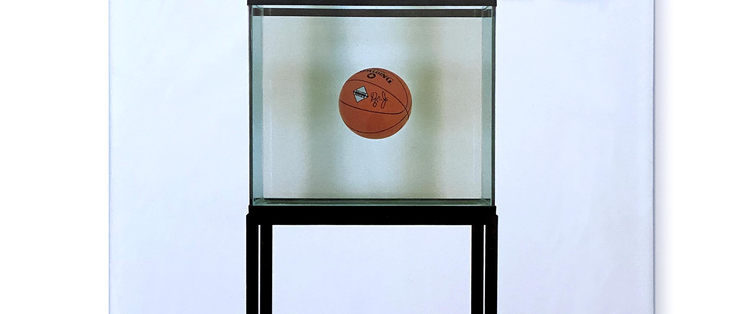 Book cover with text "Jeff Koons" at the top. Features an art piece of a single basketball floating in a glass case on a black stand. The background is white with faint, large text "Koons" partially visible.