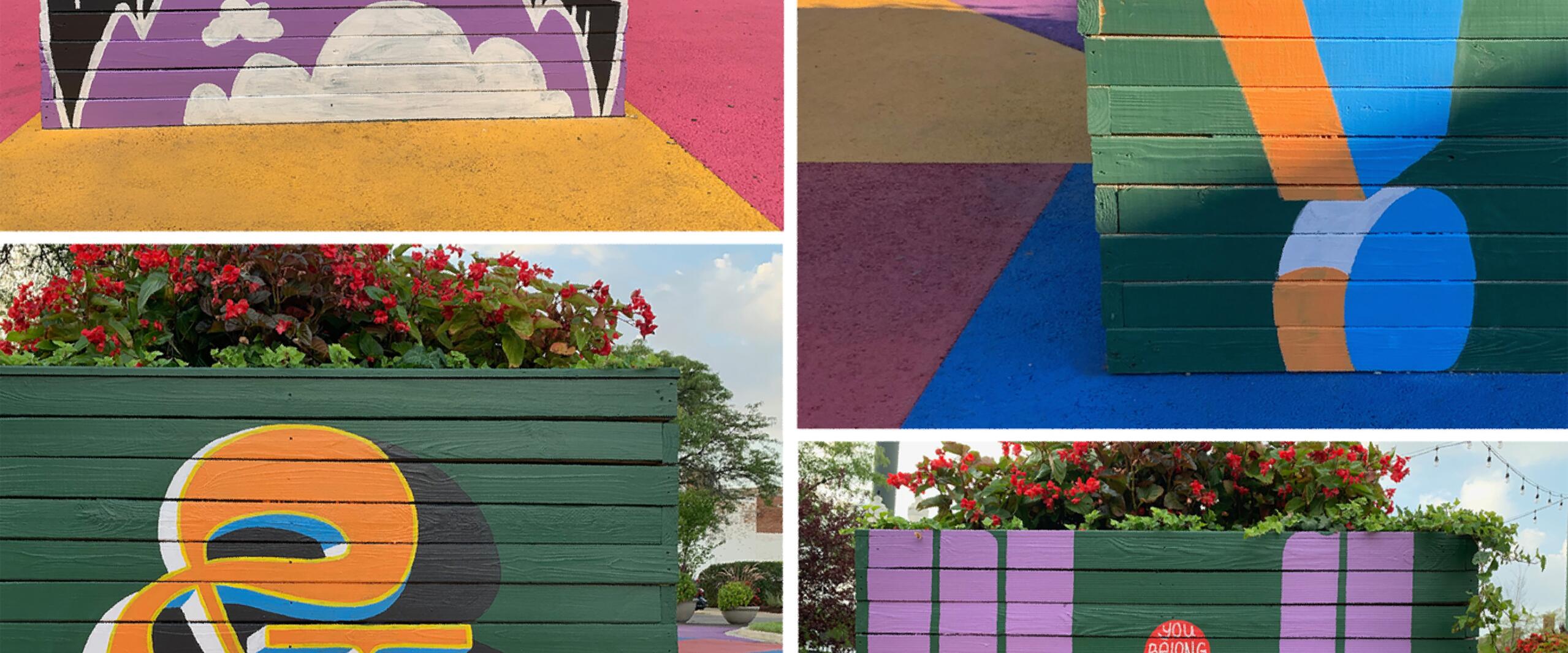 Colorful street art on planters with floral arrangements. Designs include bold lettering and abstract shapes in vibrant hues of purple, orange, blue, and green on a colorful pavement.