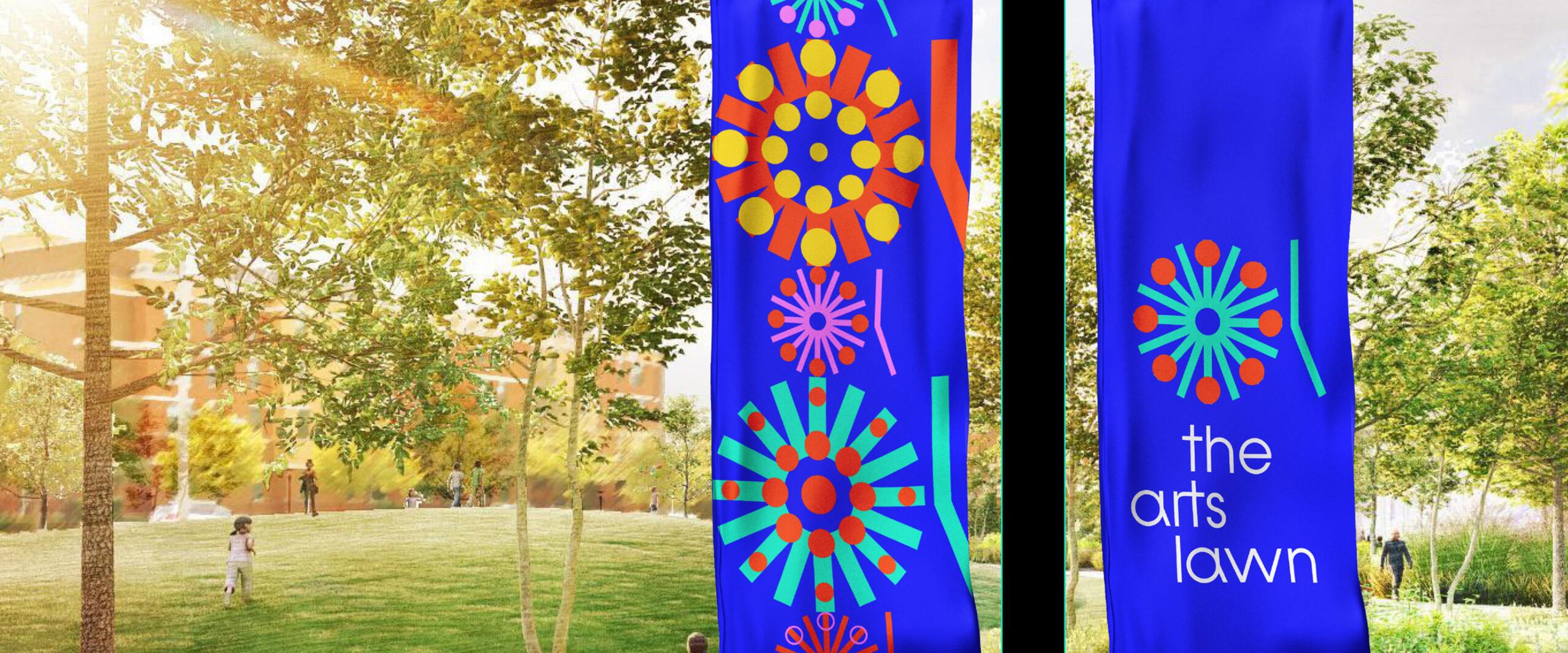 Blue banners with colorful circular designs hang on a pole in a sunlit park setting. People are scattered in the background, and sunlight filters through the trees.