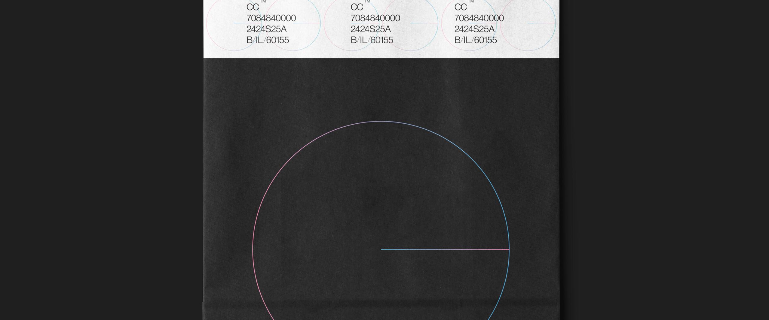 A black shopping bag with thin handles, featuring a simple geometric design of a colored circle and line. Top part displays a strip with printed text and numbers.
