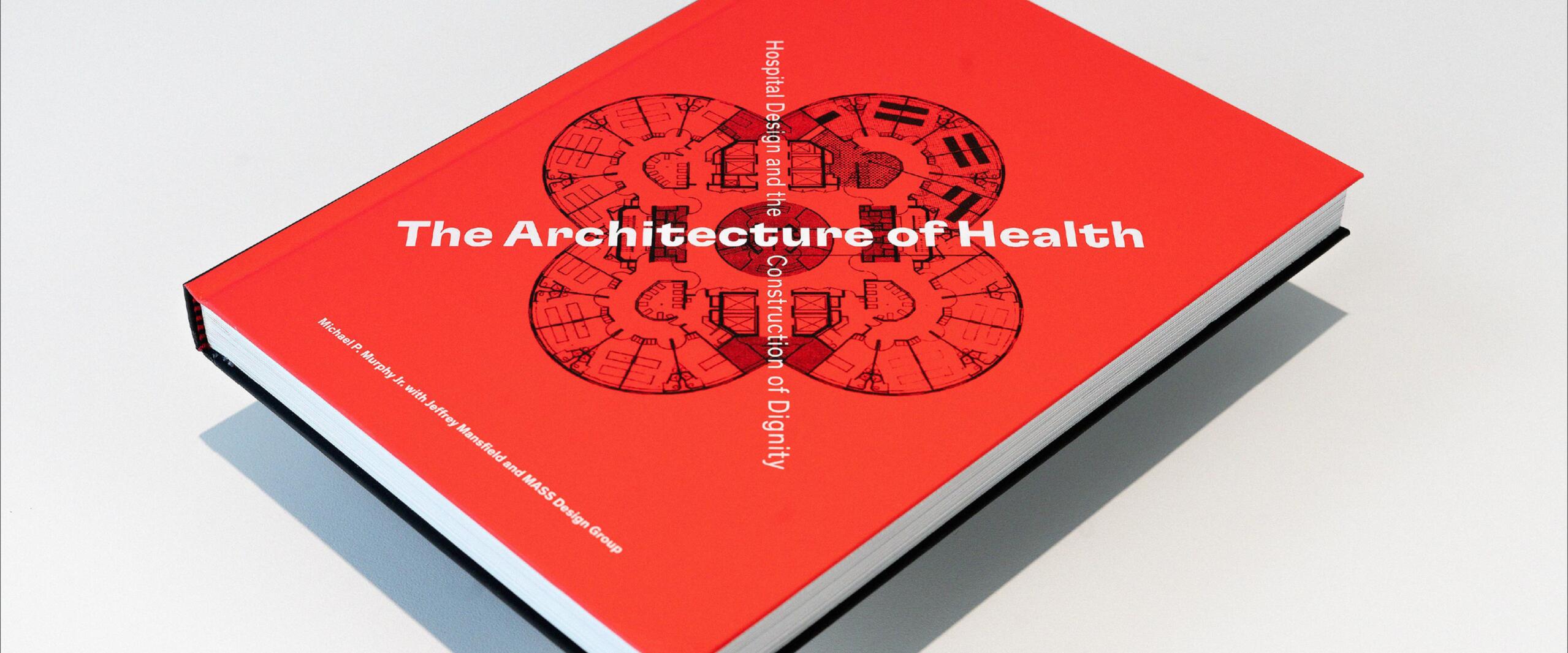 Red book titled "The Architecture of Health" on a light surface, featuring a circular architectural design sketch on the cover.