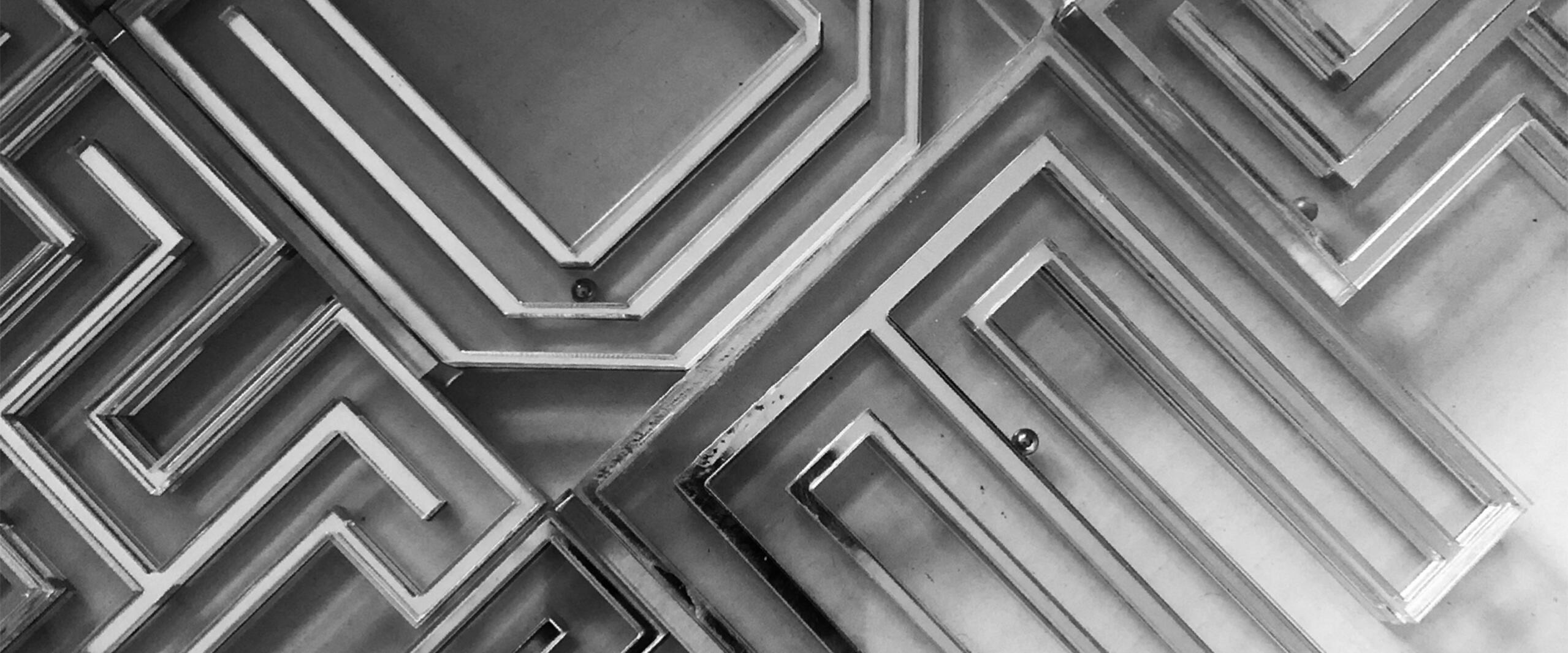 Intricate black and white geometric patterns with layered, angular shapes creating a maze-like appearance.