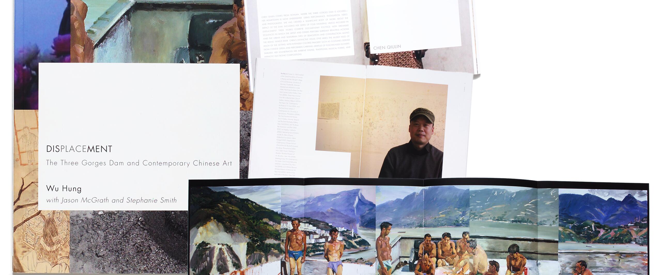 Open books and a spread featuring artwork and photographs relating to the Three Gorges Dam in China. The cover shows "Displacement" by Wu Hung. Inside, there's a portrait of a person wearing a cap and another figure in a yellow outfit. The foldout depicts people near a scenic river.