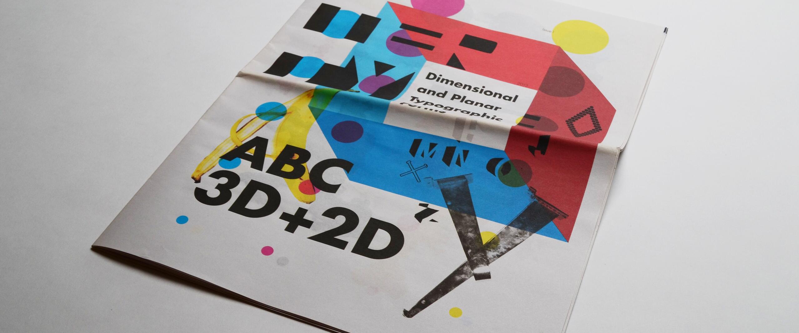 Colorful folded magazine on a white surface, featuring bold, abstract typography and graphics with bright circles and squares in red, blue, and yellow. The text is layered with artistic elements.
