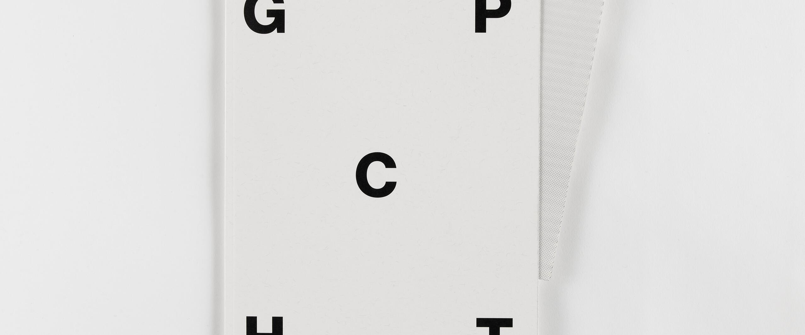 White notebook with black capital letters G, C, H, I, and P on the cover. Positioned on top of a gray dotted sheet.