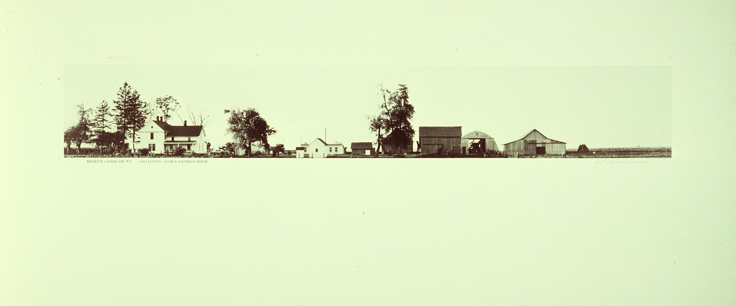 Panoramic view of a rural landscape featuring a series of farm buildings and trees, set against a wide, flat expanse.