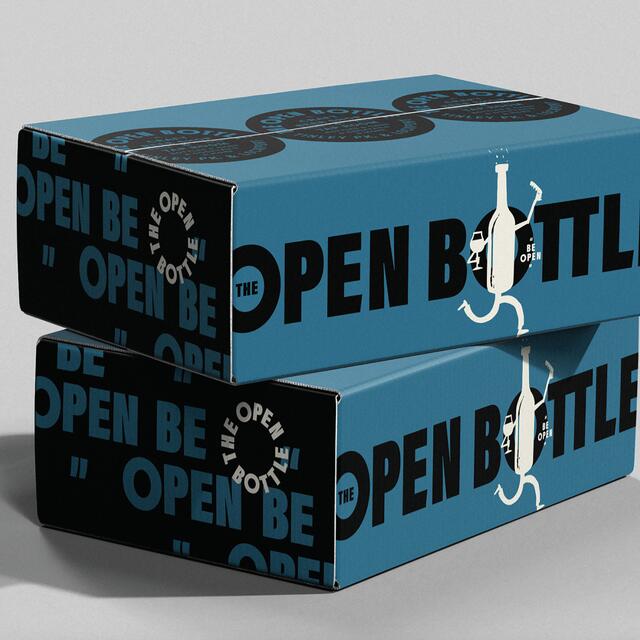 25B-05c_The Open Bottle Visual Identity: Two blue boxes stacked, featuring bold black text "The Open Bottle" and symbol of a bottle with legs_Jack Muldowney